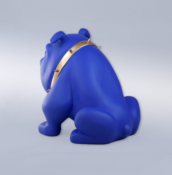 A statue of a blue dog with a gold spiked collar, facing away.