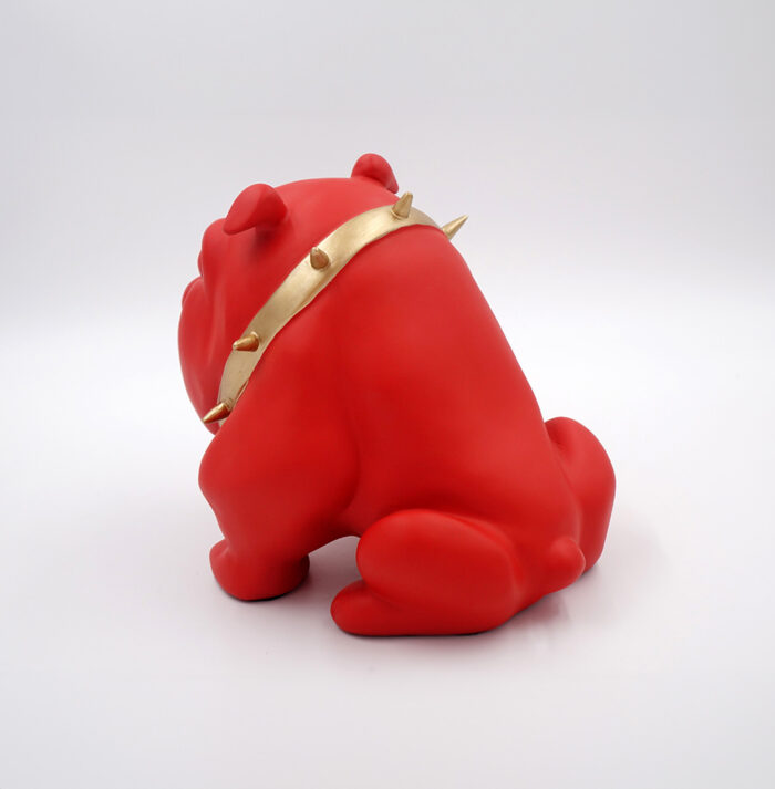 Red bulldog sculpture wearing a gold spiked collar.