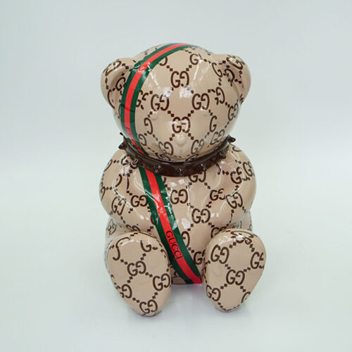 A teddy bear covered in a pattern featuring the Gucci 
