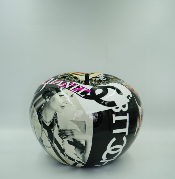 A large, shiny apple sculpture featuring a collage of black, white, and colorful images including vintage photographs, text, and recognizable brand logos.