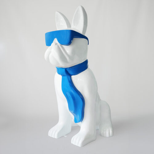 White statue of a dog wearing blue sunglasses and a blue scarf.