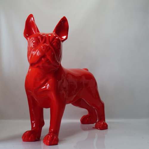 Red glossy statue of a French Bulldog standing on a white surface against a light grey background.