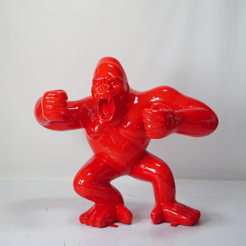 Red glossy gorilla sculpture with clenched fists and an open mouth, posed in an aggressive stance.