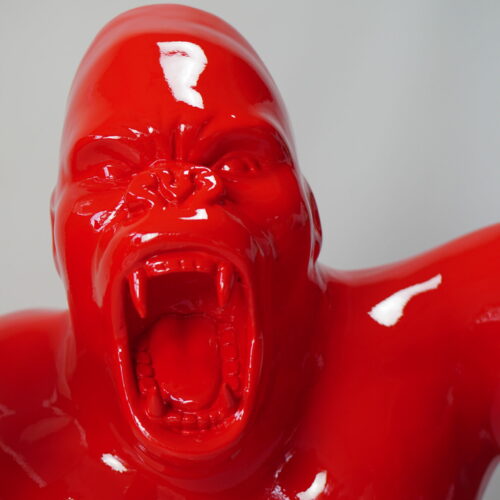 Bright red sculpture of a roaring gorilla with fangs bared.