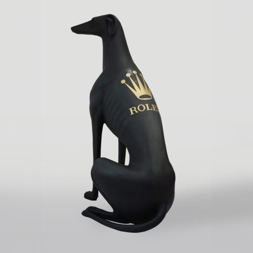 Black sculpture of a greyhound dog with a gold Rolex logo on its back.