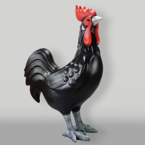 Sculpture of a black rooster with red comb and wattles, standing against a neutral background.