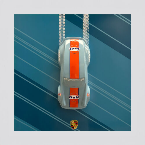 Top view of a model Porsche car with Gulf and Recaro branding, on a blue background with tire track patterns and the Porsche emblem at the bottom.