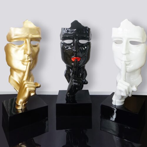 Three decorative face sculptures in gold, black, and white, each making the
