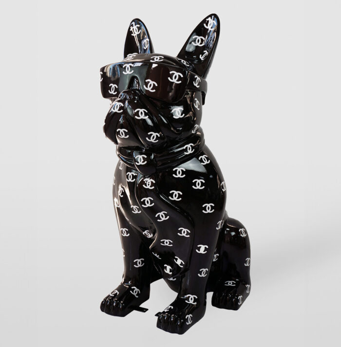 Glossy black figurine of a dog with sunglasses, covered in a pattern of white Chanel logos.