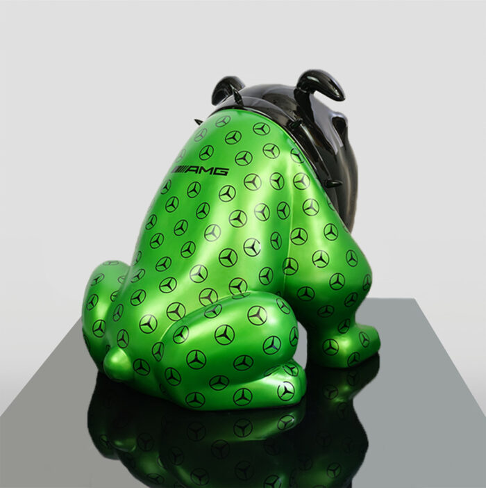 Green dog sculpture with black ears and face, covered in Mercedes-Benz logos and an AMG emblem on its back.