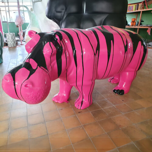 Pink and black hippo sculpture in an art studio.