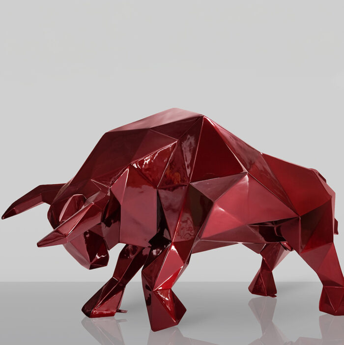 Red geometric bull sculpture with a shiny finish on a plain background.