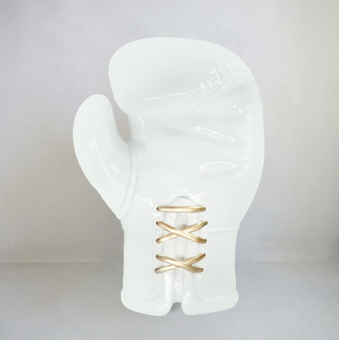 White ceramic boxing glove with gold laces on a neutral background.