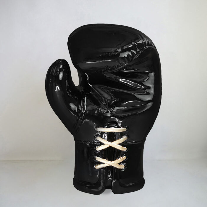 Large black glossy boxing glove sculpture with white laces.