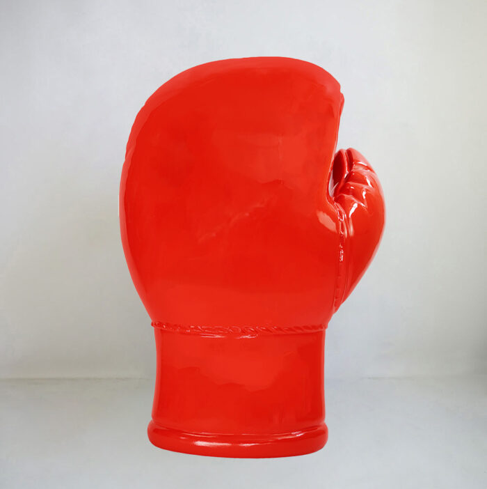 Large red boxing glove sculpture standing upright against a plain background.