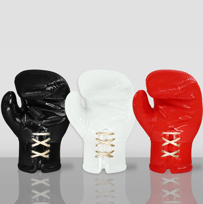 Three ceramic boxing glove sculptures in black, white, and red colors, with gold lace details.