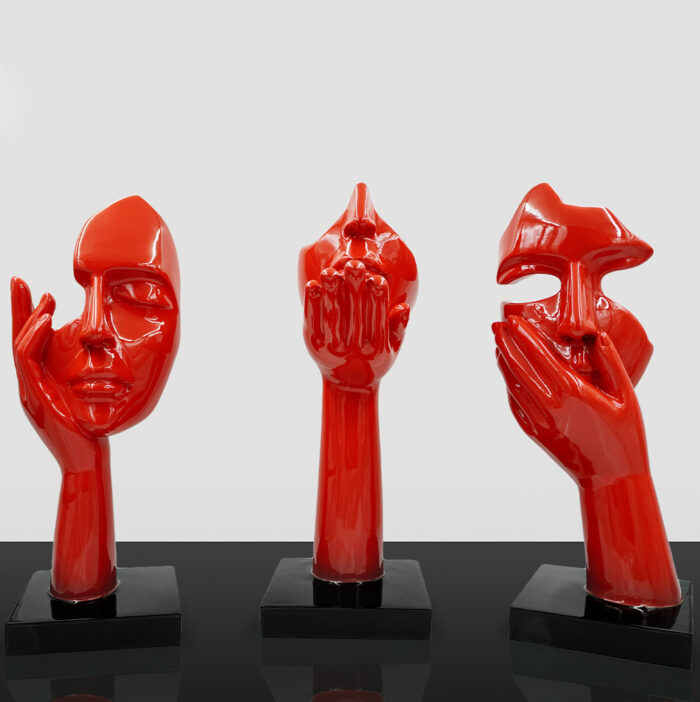 Three red abstract sculptures with facial and hand features, each displayed on a black base against a white background.