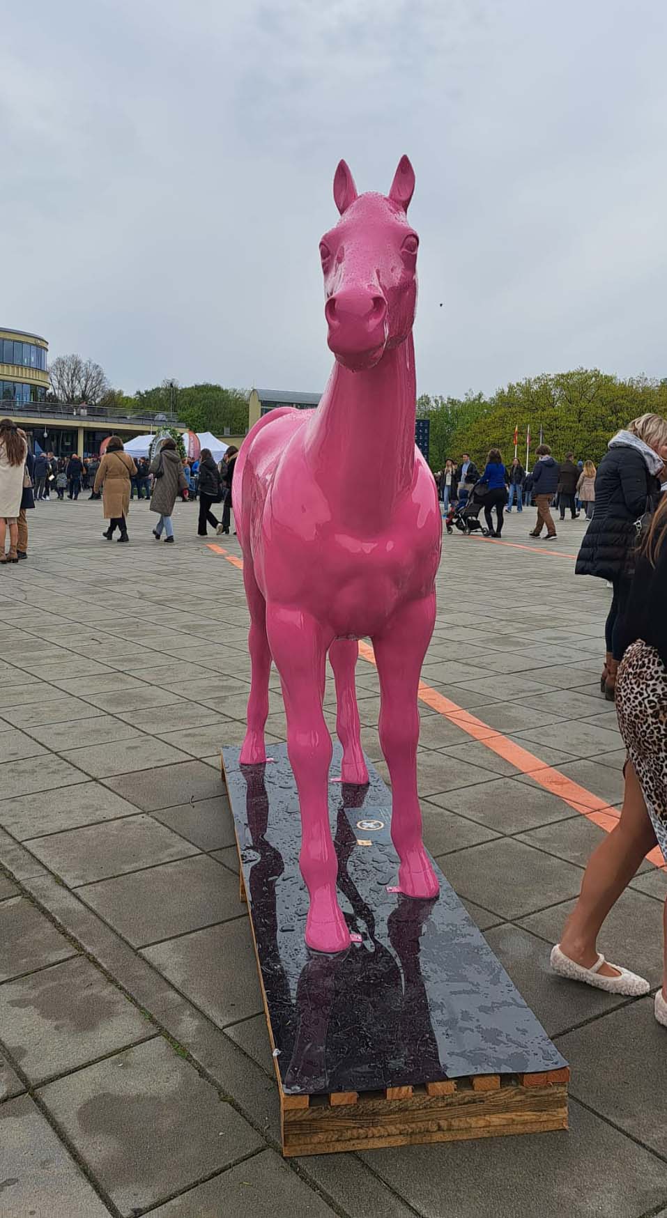 Colorful Horse Sculptures at the Partynice Racecourse in Warsaw 7 Różowa rzeźba konia na placu wśród ludzi.