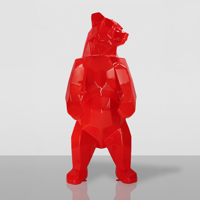 Red geometric bear sculpture standing on a reflective surface.