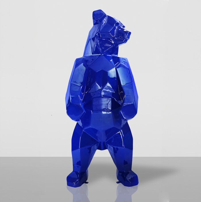 Blue geometric bear sculpture standing on a reflective surface.