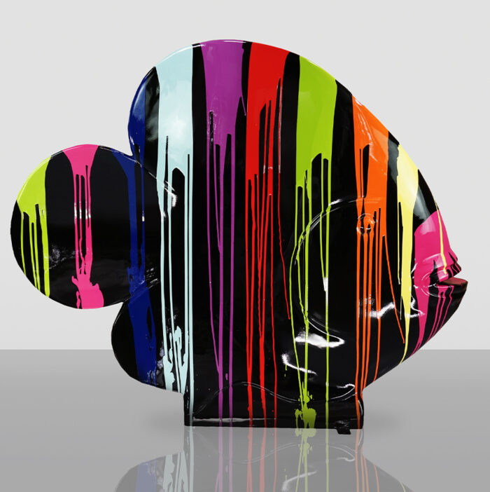 Abstract fish-shaped sculpture with multicolored paint drips on a glossy black surface.