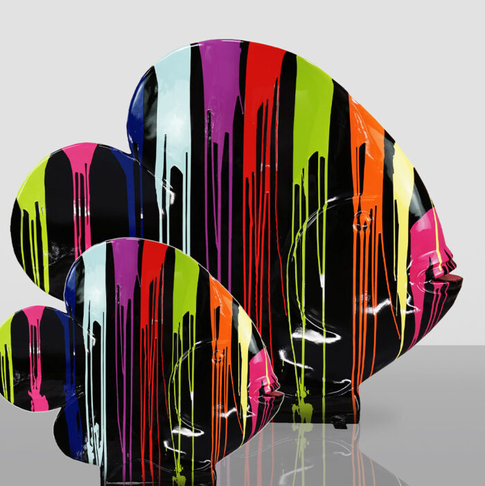 Three brightly colored fish sculptures with vertical drips of paint in black, pink, red, orange, green, blue, and purple against a light gray background.