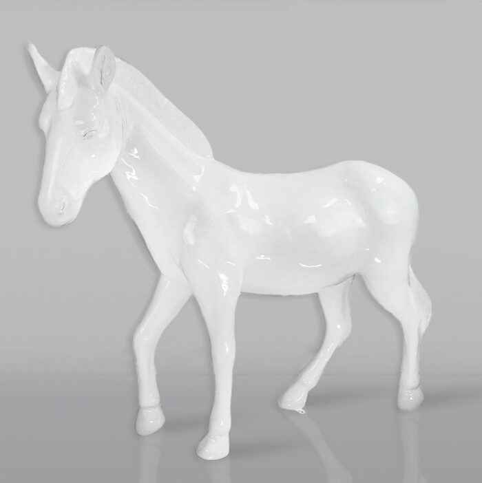 White ceramic unicorn statue on a gray background.