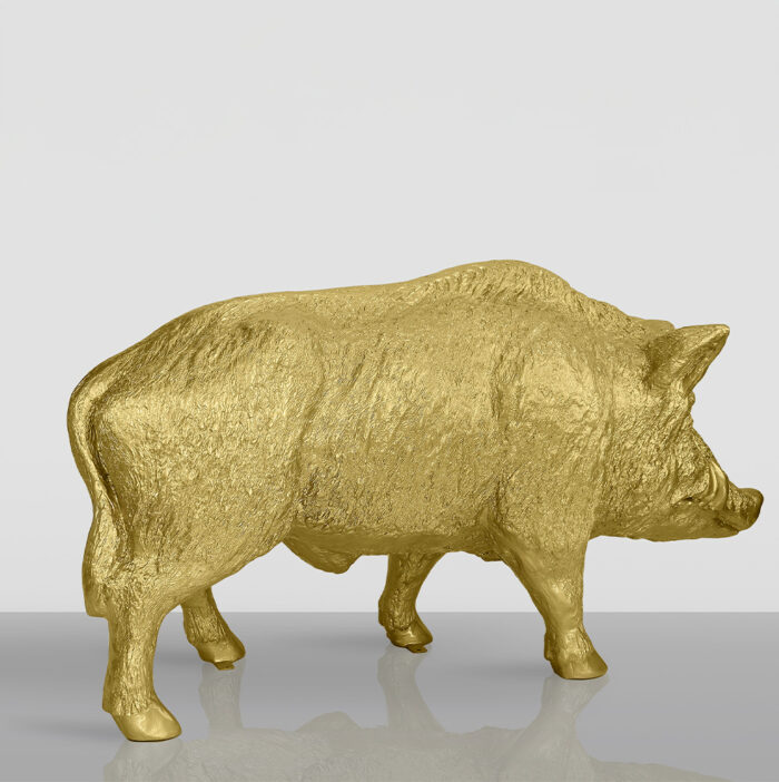 Golden pig statue on a reflective surface.