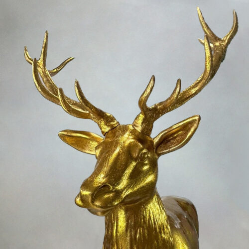 Golden deer stag sculpture with prominent antlers against a neutral background.