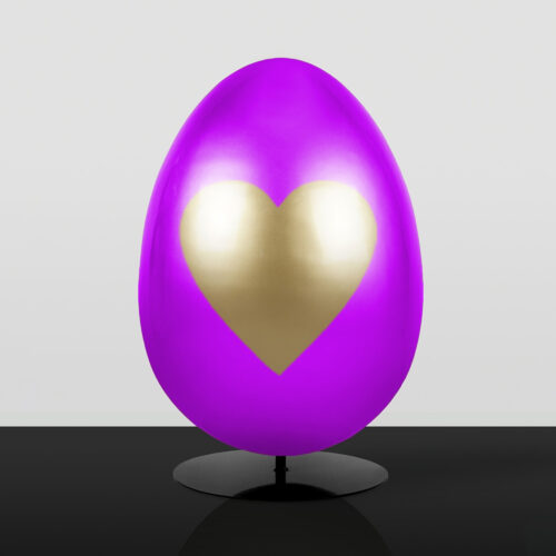 Purple egg-shaped sculpture with a large golden heart on the front, displayed on a black circular stand against a light gray background.