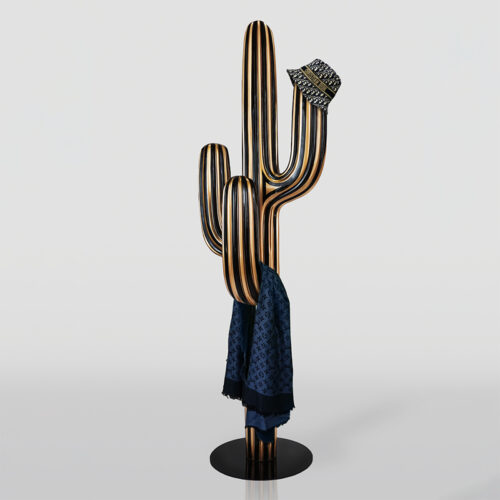 Metal sculpture of a striped cactus with a luxury patterned bucket hat on one arm and a blue designer scarf hanging on another arm against a plain light background.