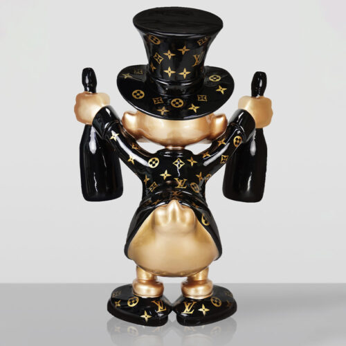 Back view of a shiny, gold and black figurine wearing a top hat and suit adorned with Louis Vuitton patterns, holding two large black bottles, standing on a reflective surface with a plain background.