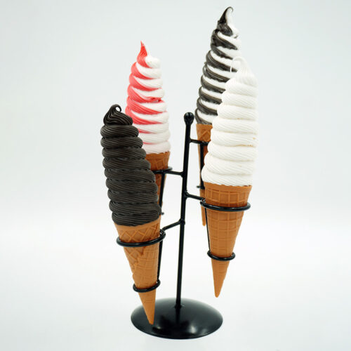 Four soft-serve ice cream cones in a black metal stand, featuring one dark chocolate, one white with red swirl, one black and white swirl, and one white cone against a plain white background.