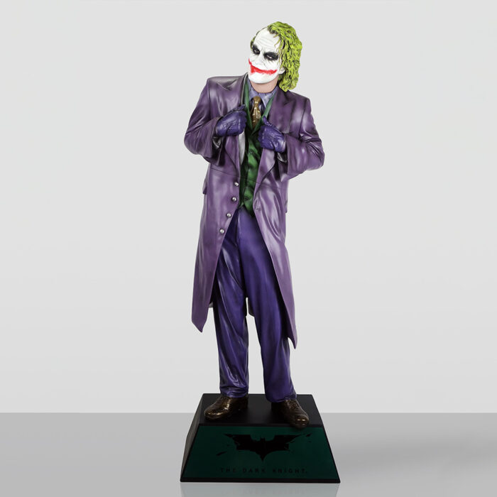 A detailed figurine of the Joker from The Dark Knight, wearing a purple suit, green vest, purple gloves, and brown shoes, standing on a black base with The Dark Knight logo and text.