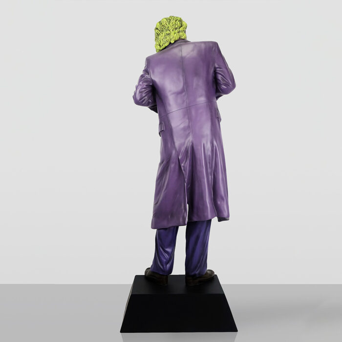 Rear view of a figurine wearing a purple long coat and matching pants, standing on a black pedestal, with bright yellow-green hair.