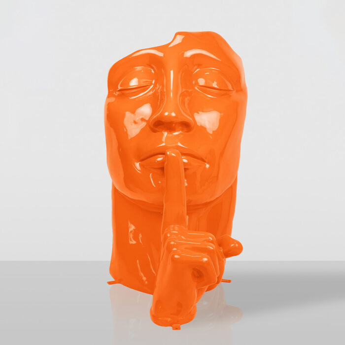 Glossy orange sculpture of a face with eyes closed and a finger held up to the lips in a shushing gesture, set against a plain gray background.