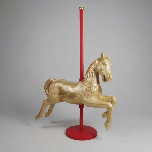 figure horse sculpture in gold-toned fiberglass with carved saddle details on a red pole base, decorative carousel style for display