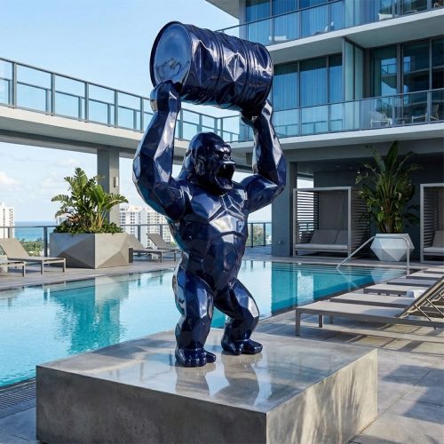 figure gorilla sculpture in glossy navy fiberglass with geometric facets holding a barrel, modern poolside decor for hotels or malls